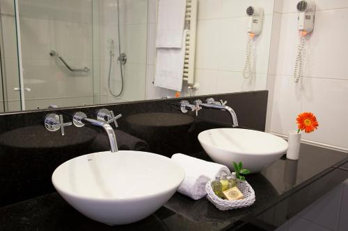 a bathroom with two sinks and a mirror at Hotel Vila Inglesa in Campos do Jordão