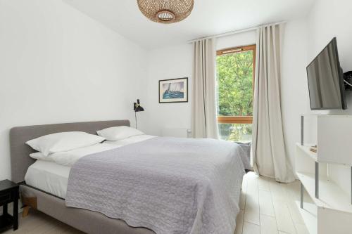 a white bedroom with a bed and a window at Cosy Apartment Parking & Balcony Close to the Kępa Redłowska by Noclegi Renters in Gdynia