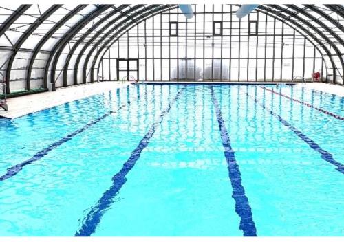 a large indoor swimming pool with blue water at Le Chastellan Twin roomChambre Twin in Péone