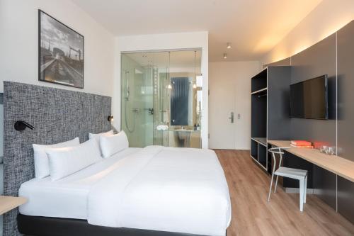 a bedroom with a large white bed and a bathroom at INNSiDE by Meliá Bremen in Bremen