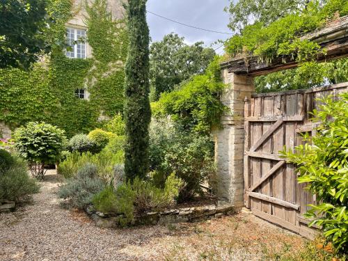 a garden with a wooden gate and a tree at Chambre d'hôtes - Suite familiale accès privatif in Sacquenay