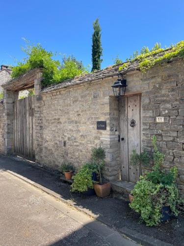 a stone building with a wooden door and plants at Chambre d'hôtes - Suite familiale accès privatif in Sacquenay