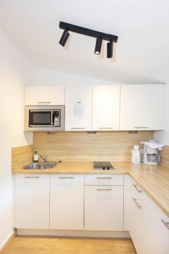 a white kitchen with a sink and a microwave at Hotel Garni Wurzer in Velden am Wörthersee