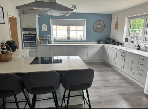 a kitchen with white cabinets and a table and chairs at Riverside View - Large, modern 4 bedroom house with hot tub in Wooler