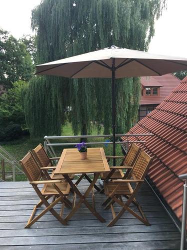 a wooden table and chairs under an umbrella on a deck at Ferienglück Lindwedel in Lindwedel