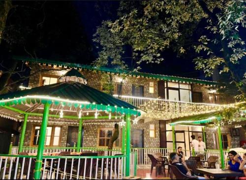 people sitting at tables in front of a building with green lights at The Boho Woods Resort in Nainital