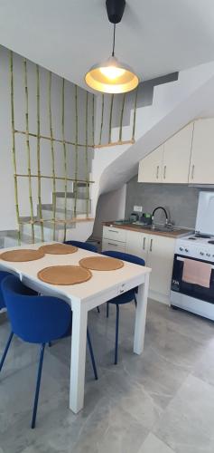 a kitchen with a white table and blue chairs at Heracles Guest house in Néa Péramos