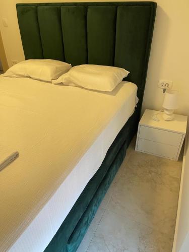a bed with a green headboard next to a table at MBv Budva in Budva