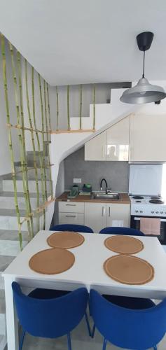 a kitchen with a white table and blue chairs at Heracles Guest house in Néa Péramos