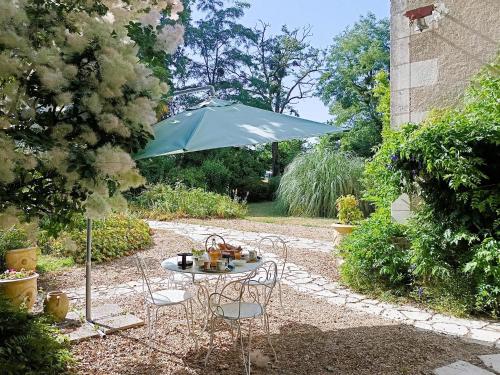 - une table avec des chaises et un parasol dans le jardin dans l'établissement Chateau de Coubloust, à Vicq-sur-Nahon