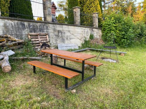 a picnic table and a chair sitting in the grass at MODRZEW - noclegi w Pyzówce in PyzÃ³wka