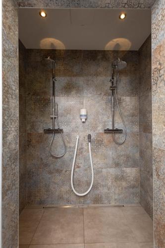a bathroom with two shower heads and a wall at Hotel Garni Wurzer in Velden am Wörthersee