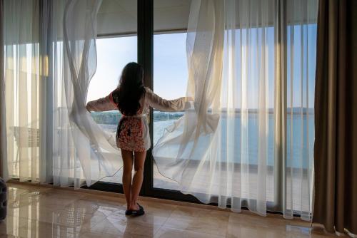 a woman looking out of a window at the ocean at Paradiso Dreams Hotel in Nesebar