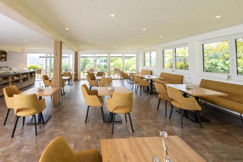 a restaurant with tables and chairs and windows at Hotel Garni Wurzer in Velden am Wörthersee