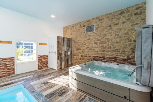 a large bathroom with a tub and a brick wall at La Belle Hermine in Tonquédec