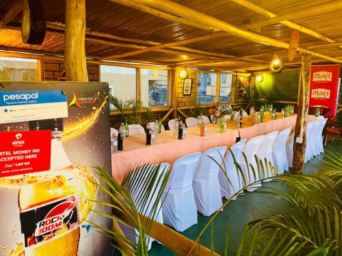 a row of white chairs and tables in a room at Citizen Cafe & Chambers in Mbale
