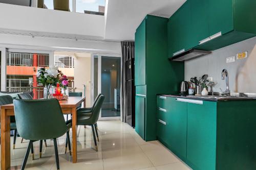 a kitchen with green cabinets and a table with chairs at Luxurious Penthouse Pattaya in Pattaya South