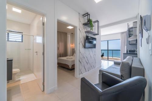 Una sala de estar con un sofá y una silla y un baño. en HY Apart, en Bombinhas