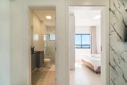 Un dormitorio con una cama y un baño con lavabo. en HY Apart, en Bombinhas