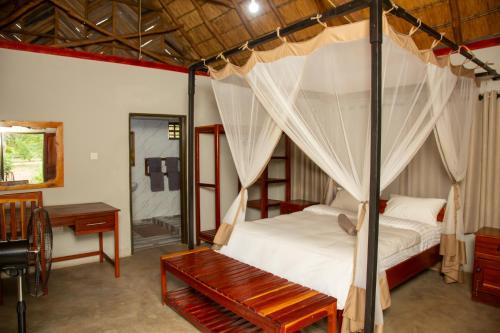 a bedroom with a canopy bed with a bench and a desk at Oxpecker Safari Lodge 