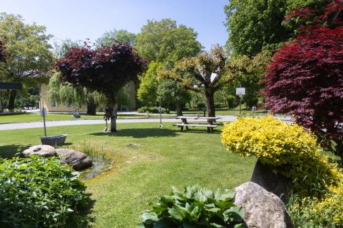 a park with a bench and flowers and trees at Hotel Garni Wurzer in Velden am Wörthersee