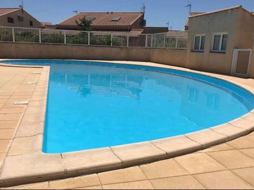 une grande piscine bleue dans une cour dans l'établissement Maison avec Mezzanine, 5 Couchages, Piscine, Près Plage - Gruissan - FR-1-229-845, à Gruissan
