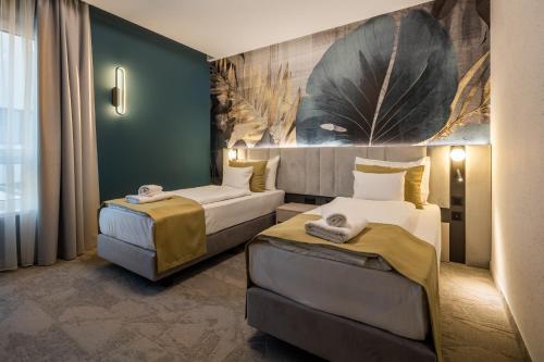 a hotel room with two beds and a painting on the wall at Energy Hotel & Business Center in Paks