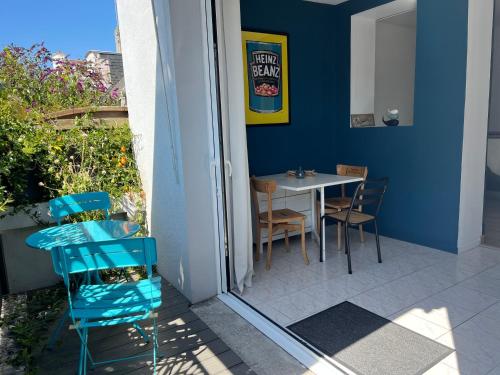 un patio avec une table et des chaises et un mur bleu dans l'établissement Hébergement retour de plage, à Tréffiagat