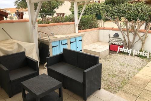 un patio avec deux chaises et une cuisine avec un grill dans l'établissement Beach house, à Frontignan