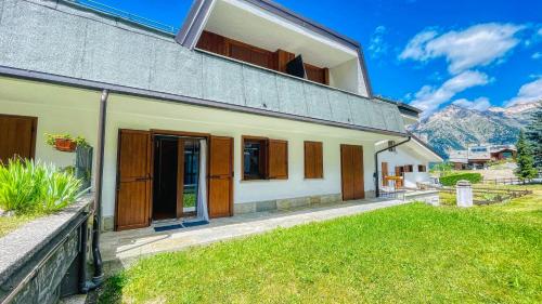 a house with a green lawn in front of it at Appartamento Il Laghetto - Affitti Brevi Italia in Sauze d'Oulx