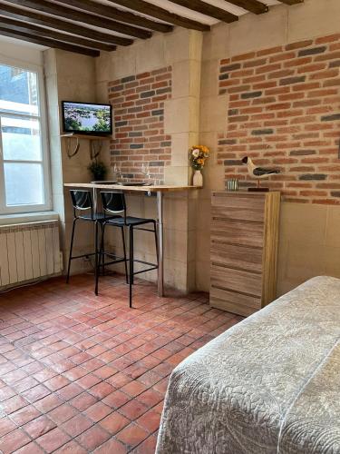 Cette chambre dispose d'une table et d'une télévision sur un mur en briques. dans l'établissement Appartement Des Lingots, à Honfleur