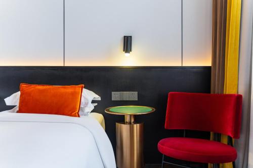 a hotel room with a bed and two red chairs at HeSu Hidden Art Hotel & Suites - Near Bell Tower & Ideal Location-Spacious rooms featuring King or Double Queen beds -Exclusive Two&Three-Bedroom Suites with Expansive Living Rooms for Group Gathering-Kitty Cuddles & Coffee Gift -Seamless Journey Planning in Xi'an