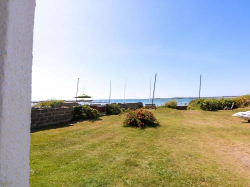 a grassy yard with a view of the ocean at Windygates in Rhosneigr