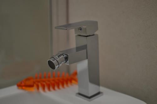 a bathroom sink with a faucet and orange brushes at Hotel Vienna in Pesaro