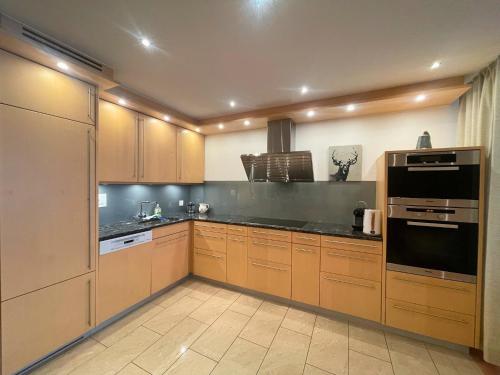 a large kitchen with wooden cabinets and black counter tops at Laax Rancho Residence in Laax