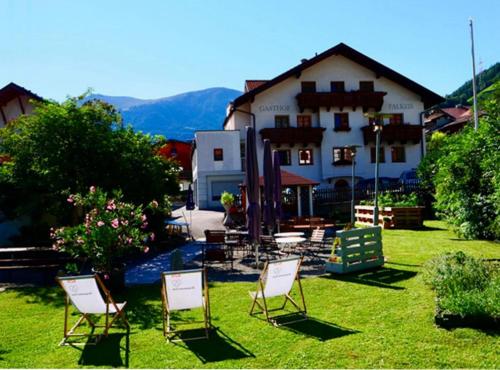 a group of chairs sitting in the grass in front of a building at Gasthof Falkeis in Kauns