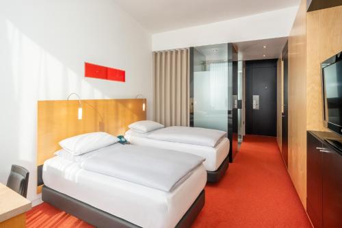 a hotel room with two beds and a flat screen tv at INNSiDE by Meliá Düsseldorf Seestern in Düsseldorf