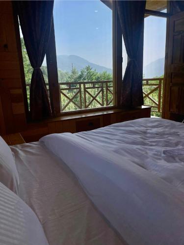 a bedroom with a bed and a window with a view at The Highgrove House, Manali in Haripūr