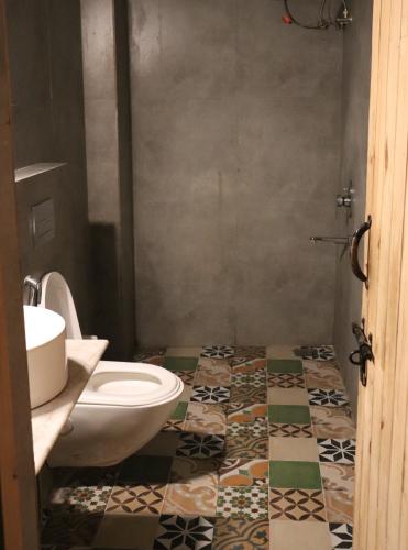 a bathroom with a toilet and a tile floor at Bunkyard in Udaipur