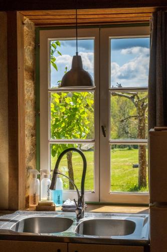 une cuisine avec un évier et une fenêtre dans l'établissement Camping la Jaurie hébergements, à Ladignac-le-Long