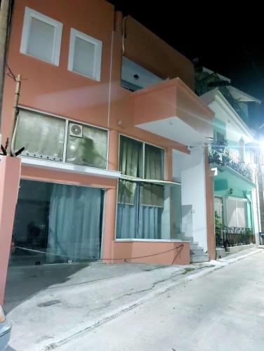 a pink and white building with windows at night at ATHENA'S Central APP in Samos