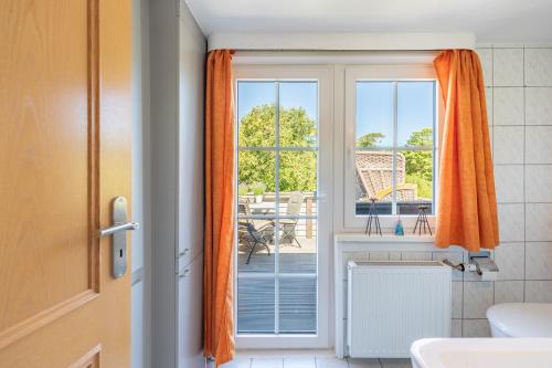 an open door to a balcony with an orange curtain at Nordsee pur in Husum