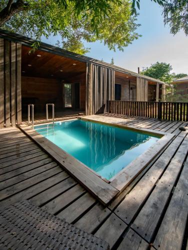 a swimming pool with a wooden deck and a house at Green Villa Near Bishkek in Këk-Dzhar