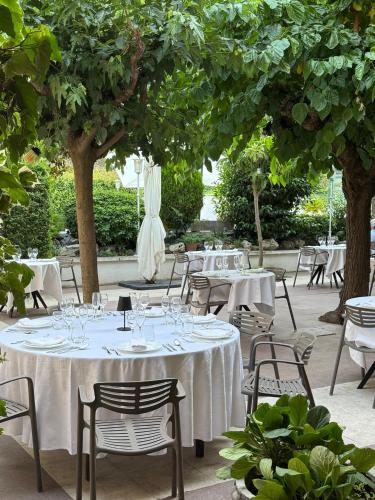a table with white table cloths and chairs and trees at Hotel Robert in La Pobla de Claramunt