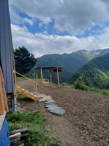 a wooden shelter on a hill with mountains in the background at Mariiko's cottages in Davberi