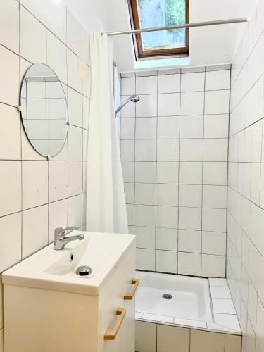 une salle de bain blanche avec un lavabo et un miroir dans l'établissement Appartement avec grand espace vert, à Cauterets