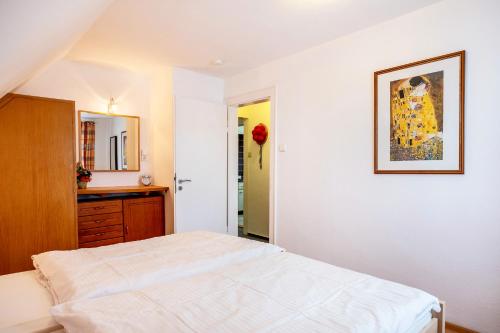 a white bedroom with a bed and a mirror at Haus Marianne Duffner in Schonach