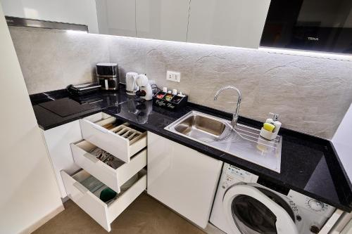 a kitchen with a sink and a washing machine at Apartamentos Golfinho Dourado in Santa Maria