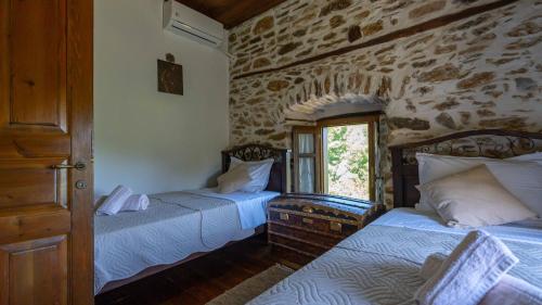 a bedroom with two beds and a stone wall at Μountain Whispers in Mouresi