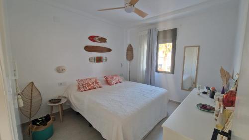 ein weißes Schlafzimmer mit einem Bett und einem Deckenventilator in der Unterkunft Akunamatata in Oliva